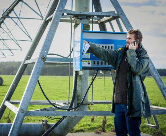 Farmer on phone at irrigation machine